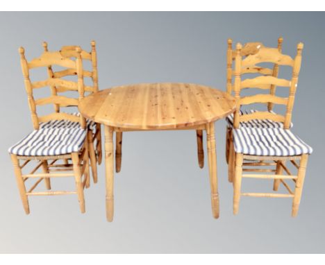 A circular pine extending kitchen table together with four ladder backed pine chairs and further pair of spindle backed chair