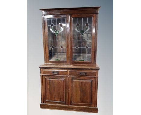 An Art Nouveau mahogany double door bookcase with leaded glass doors  