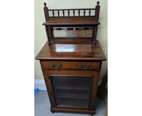 An Arts &amp; Crafts mahogany cabinet, single drawer over glass door, upper shelf with integrated bevelled plate mirror.