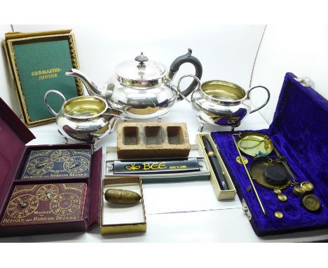 A silver plated three piece tea service, a set of balance scales and weights, an Addmaster adding machine, harmonica, a Conwa