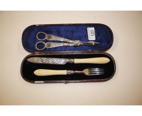 A pair of silver plated grape scissors; and a Victorian silver bladed knife and fork