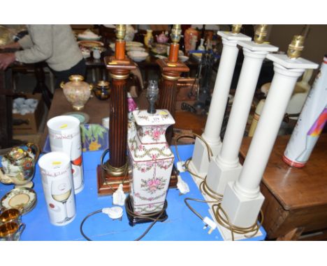 A pair of wooden Corinthian column table lamps; and a rose decorated table lamp