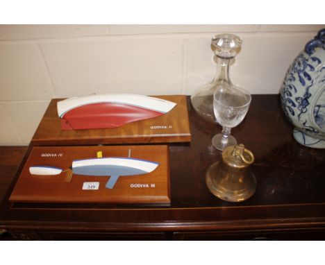 Two half model boat hulls, together with a bell, a decanter, and wine glass all relating to the boat Godiva