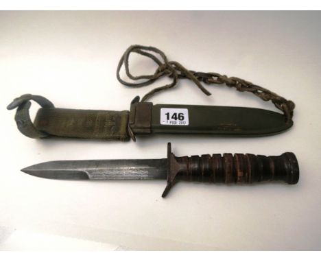 An American US combat fighting knife, pressed leather hand grip, steel pommel stamped with flaming ball device, hard plastic 