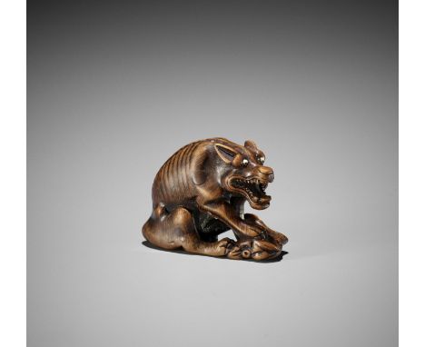 MASATOMO: A WOOD NETSUKE OF A WOLF WITH HAUNCH OF VENISONBy Masatomo, signed Masatomo 正友Japan, early 19th century, Edo period