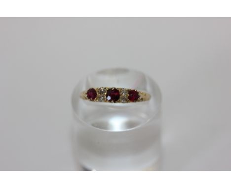 A ruby and diamond ring claw set with three graduated round rubies and pairs of old cut diamonds between, in 18ct gold, circa