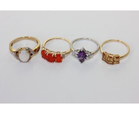 An opal and diamond ring in 9ct gold, an amethyst ring, a fire opal ring and a three stone ring