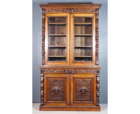 A Late Victorian Oak Chiffonier Bookcase, the whole carved with lions' masks, fruit and leaf scroll ornament, the upper part 