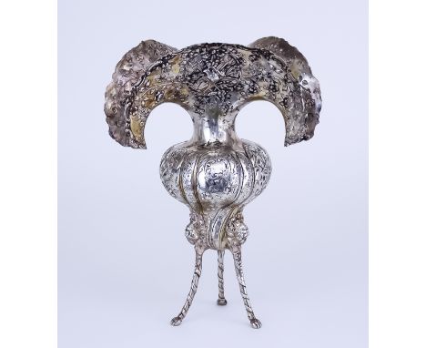 A Continental Silvery Metal Vase, the deep shaped rim with scroll and floral mounts, embossed with harvesting tools within ri