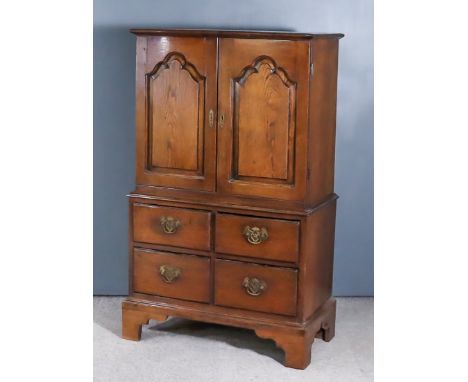 A Small Oak Cabinet of "18th Century" Design, the upper part fitted one shelf enclosed by a pair of shaped and raised panelle