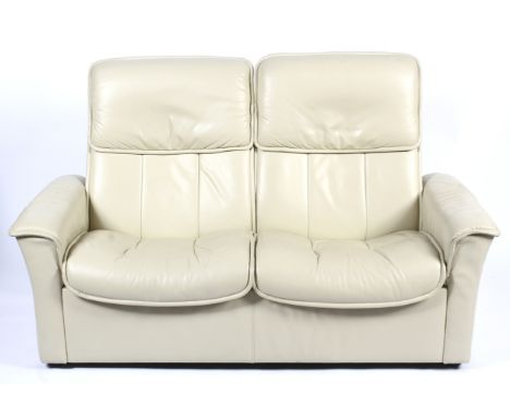 A Stressless reclining chair, a footstool and a two-seater sofa. All upholstered in cream leatherette, on circular chromed su