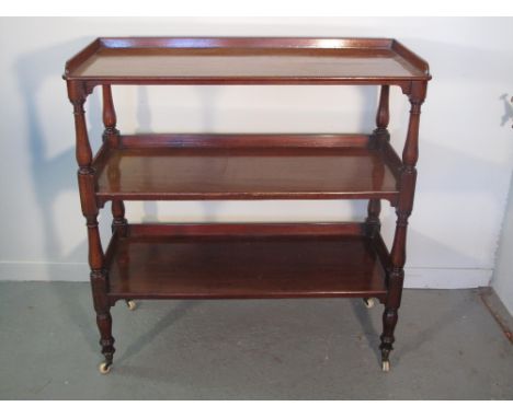 19th Century mahogany three tier dumb waiter having solid galleries, baluster turned gun barrel supports on baluster tapering