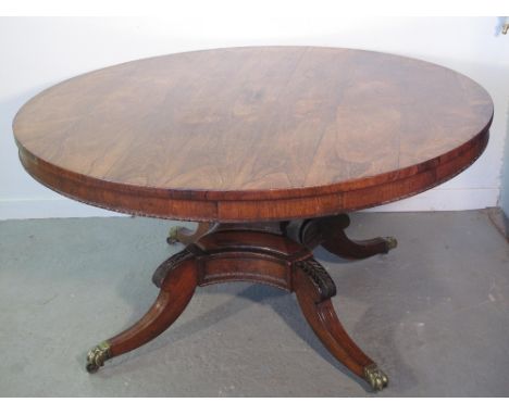 REGENCY ROSEWOOD CIRCULAR PILLAR DINING TABLE 
The top with bead moulded frieze, on a panelled tapering pedestal, on quatrafo