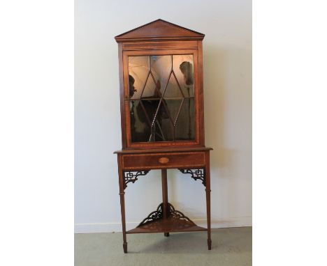 EDWARDIAN MAHAGONY INLAID CORNER CABINET ON STAND having architectural pediment over cross-banded frieze with single cross ba