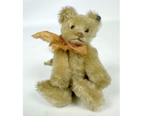 Miniaturteddy, Steiff. Weißer Mohair. Drehkopf mit Schuhknopfaugen. Gegliedert. Mit Knopf und US-Zone-Fähnchen. L. bespielt. 