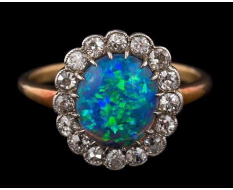 A black opal and diamond oval cluster ring: the central oval black opal approximately 10mm long x 8.3mm wide x 3mm deep, disp