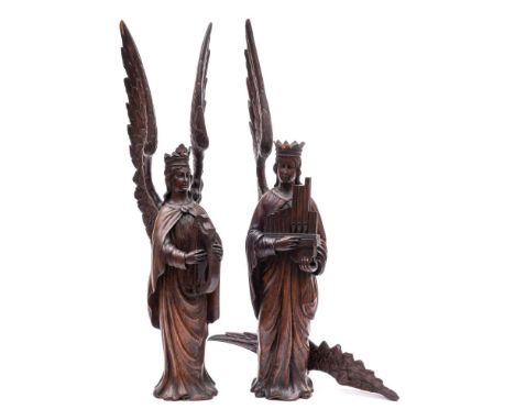 A pair of 19th Century Continental carved oak figures of angels: each with outstretched wings, wearing a crown and robes, one