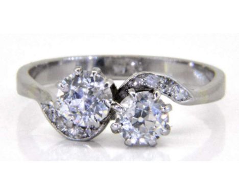 A diamond two-stone cross-over ring: with round old, brilliant-cut diamonds, 5.2mm diameter x 3.6mm deep and 5.4mm diameter x