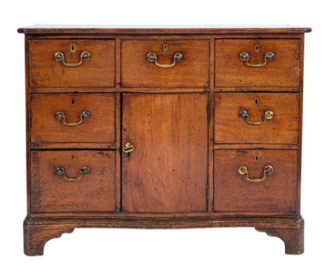 A George III mahogany serpentine fronted side cabinet:, fitted with seven deep drawers about an enclosed cupboard, on bracket