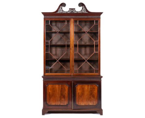 A late 19th Century mahogany bookcase in the Georgian taste:, the upper part with a pierced fret swan neck broken pediment wi