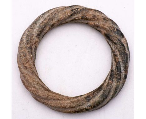 A Chinese calcified jade bangle: of archaic form, carved as a continuous twisted rope, 11cm.