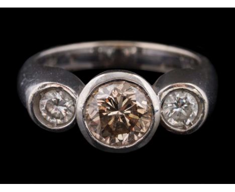 A diamond three-stone ring: with central light brown diamond approximately 6.8mm diameter x 4.4mm deep, estimated to weigh 1.