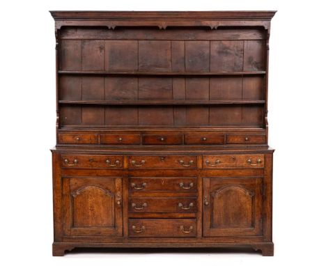 An 18th Century oak dresser,: the superstructure with moulded frieze over open shelves and five short drawers above base, fit