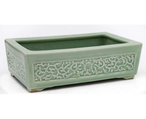 A Chinese celadon jardiniere: of squat rectangular form, each side moulded with a panel of lotus scroll, impressed apocryphal