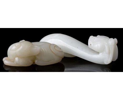 A Chinese celadon jade carving of a dog and a dragon belt hook: the dog recumbent with its head turned looking over its back,