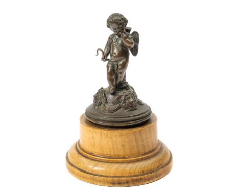 A 19th Century bronze study of Cupid: on a domed base with female mask decoration, mounted on a turned wood plinth overall he