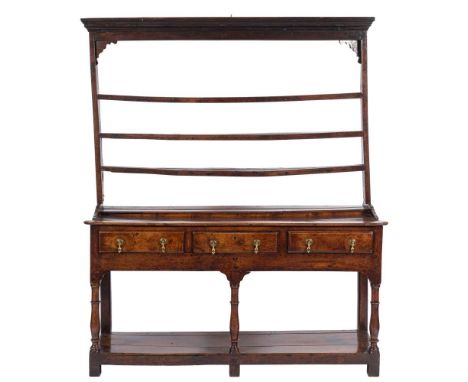 An 18th Century oak dresser:, the shelved superstructure with a moulded cornice and shaped spandrels, the base with projectin