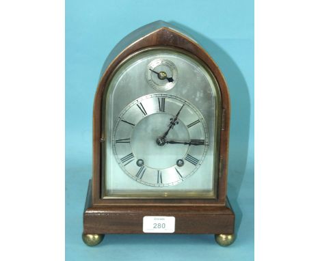 An early-20th century mahogany mantel clock, the lancet-shaped case with arched silvered dial with slow/fast subsidiary, the 