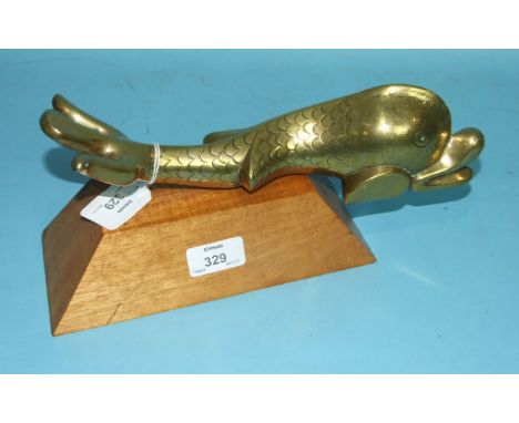 A large brass dolphin door knocker, 28cm long, on wooden plinth.