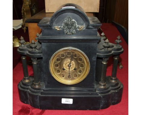 A black slate mantel clock of architectural form, the brass dial with Arabic numerals, the gong-striking movement stamped 'J 