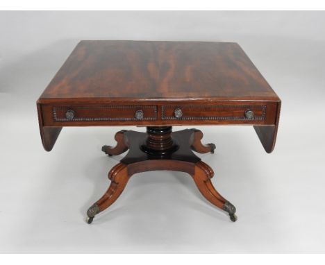 A Regency mahogany rosewood crossbanded sofa table, the two true drawers opposed by false drawer fronts, the drop leaves with