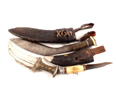 A Kukri with horn grip within its leather scabbard, with an eastern knife and a sheath knife