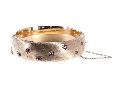 9ct yellow gold ruby set hinged bangle with safety chain, Birmingham 1964, band width 18mm, 33.8gm