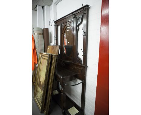 A VICTORIAN MAHOGANY HALL STAND, THE CENTRAL OVAL MIRROR OVER SHELF, CARVED DECORATION THROUGHOUT, THE BASE WITH CENTRAL DRAW