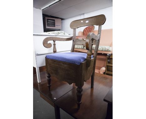 A DARK WOOD COMMODE CHAIR, SINGLE BACK RAIL SUPPORTS, SCROLL ARMS, PAD FEET ON TURNED FRONT SUPPORTS 