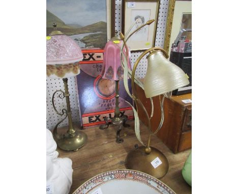 A brass table lamp, in the manner of Benson, on three shaped supports in the Arts and Crafts style, with a pink glass shade, 