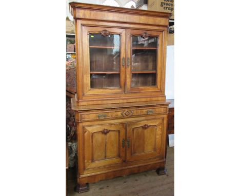 A 19th century French walnut cabinet, the upper section having a pair of glazed doors revealing shelves, the base fitted with