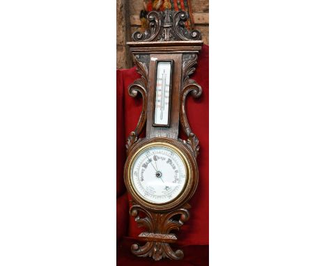 A carved and moulded oak aneroid barometer, with white ceramic dial and thermometer scale, circa 1900, approx. 95 cm h 