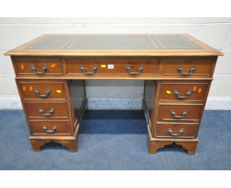 A 20TH CENTURY YEWWOOD TWIN PEDESTAL DESK, with a green tooled leather writing surface, fitted with eight drawers, on bracket