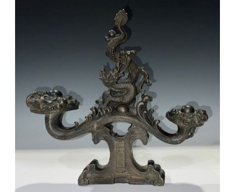 A Chinese dark patinated bronze stand, the central support cast with a fire breathing dragon, flanked by a pair of pedestals,