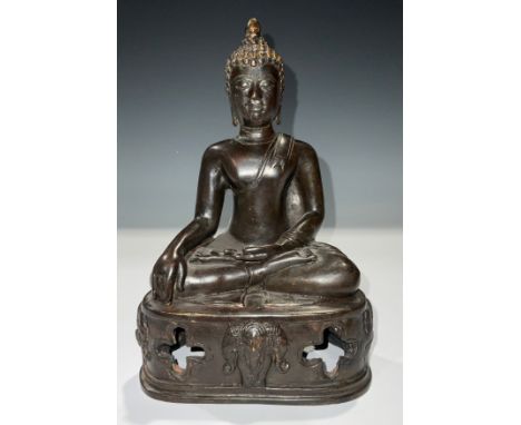 A dark patinated bronze deity, sat cross-legged, 21cm 