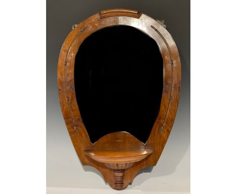 An early 20th century horseshoe shaped walnut looking glass, bevelled mirror plate, with single shelf, 61cm high 