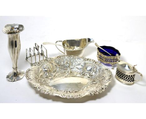 A group of silver comprising; a repousse oval dish; mustard pot and salt with pierced sides; posy vase; toast rack; cream jug