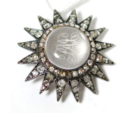 A diamond and rock crystal star brooch, a cental cabochon rock crystal engraved with a monogram, within a star frame set thro