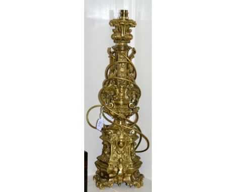 A gilt metal candlestick as a table lamp in Renaissance style, cast with classical ornament and scrolling foliage on scroll f