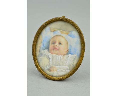 EARLY 20TH CENTURY PORTRAIT MINIATURE OF A BABY, wearing broiderie anglaise gown, head resting on a blue pillow in a crib, ov